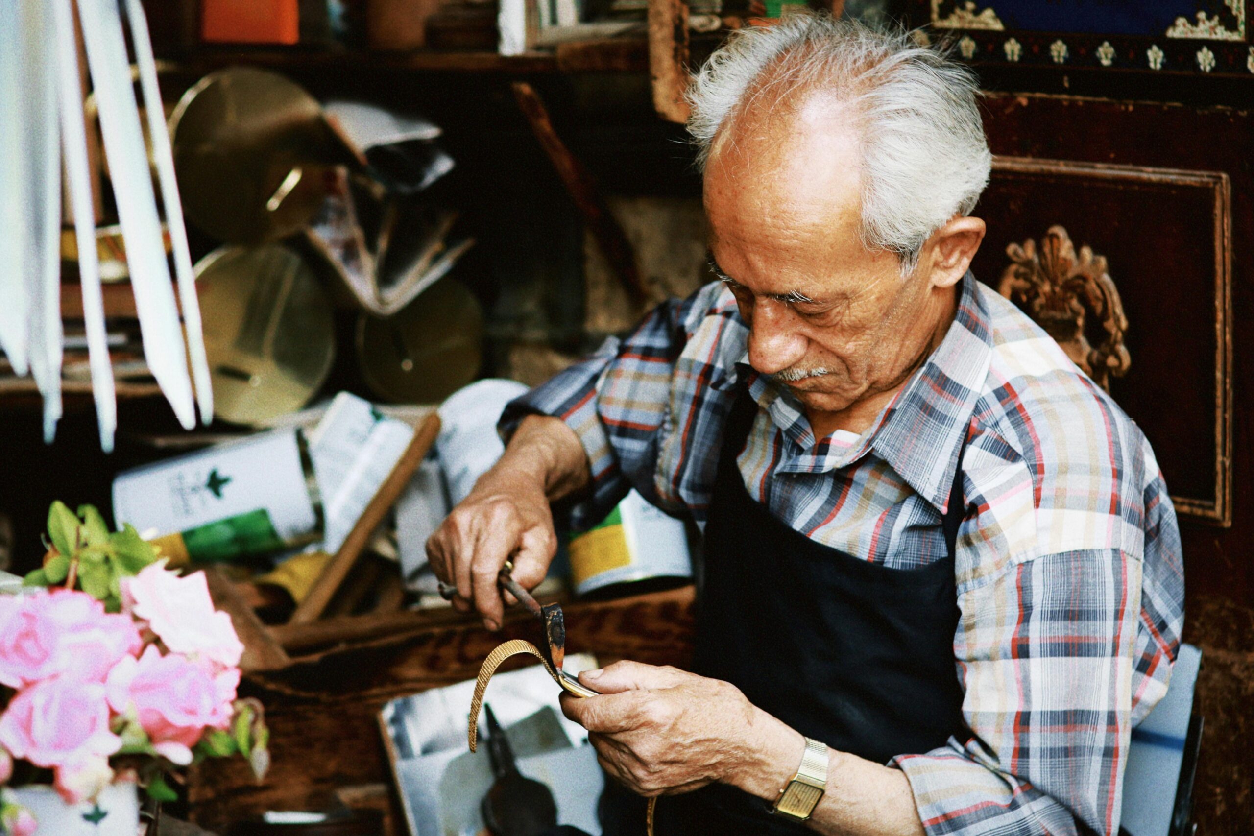 Älterer Handwerker bei der liebevollen Herstellung eines nachhaltigen Halsbands aus Apfelleder. Das Bild symbolisiert Handwerkskunst und Sorgfalt in der Produktion umweltfreundlicher und tierfreundlicher Produkte.